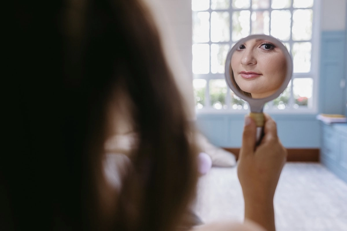 女性對著鏡子檢視臉部皮膚狀態